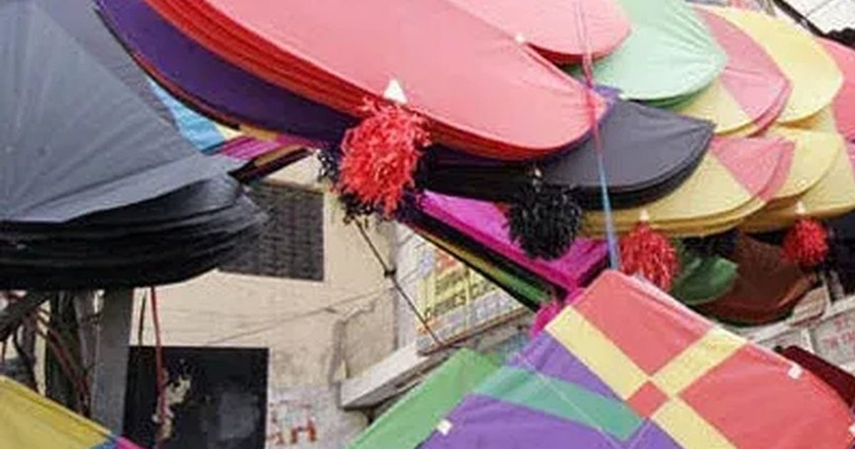 Large guddas stacked on a Lahore kite stall, a buyer lifting one from the pile