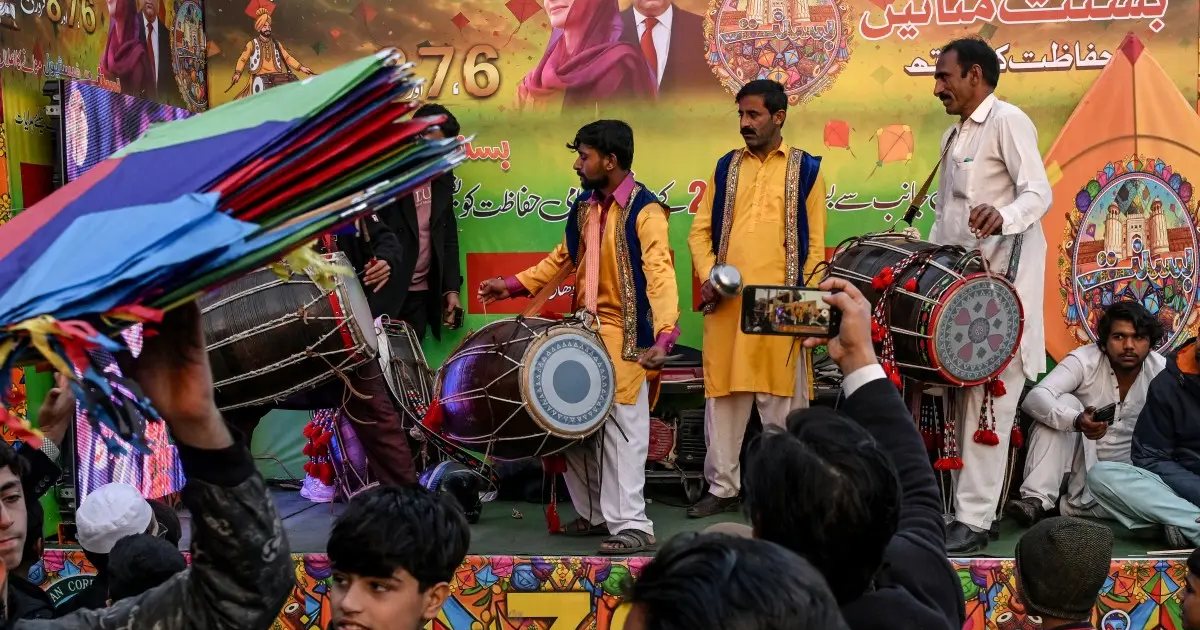Dhol players performing on a Basant stage in Lahore beneath an official festival banner