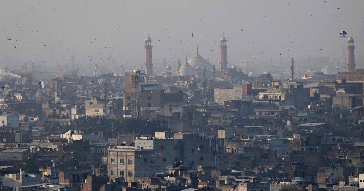 A wide view of the Lahore skyline dense with kites, the Badshahi Mosque minarets in the haze