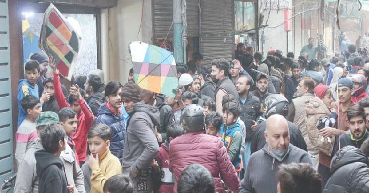 A crowded Lahore bazaar lane, buyers holding kites outside the shops before Basant