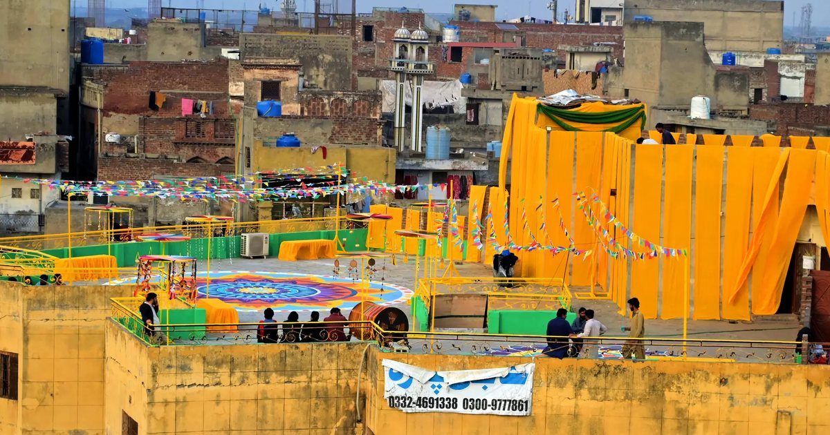 A rooftop in Lahore dressed in yellow drapes and bunting for Basant, the old city behind