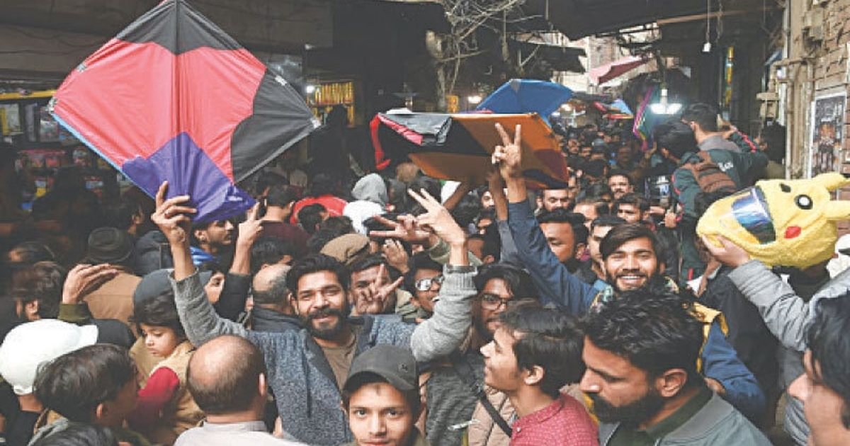 A crowded kite bazaar with buyers holding kites above the crowd