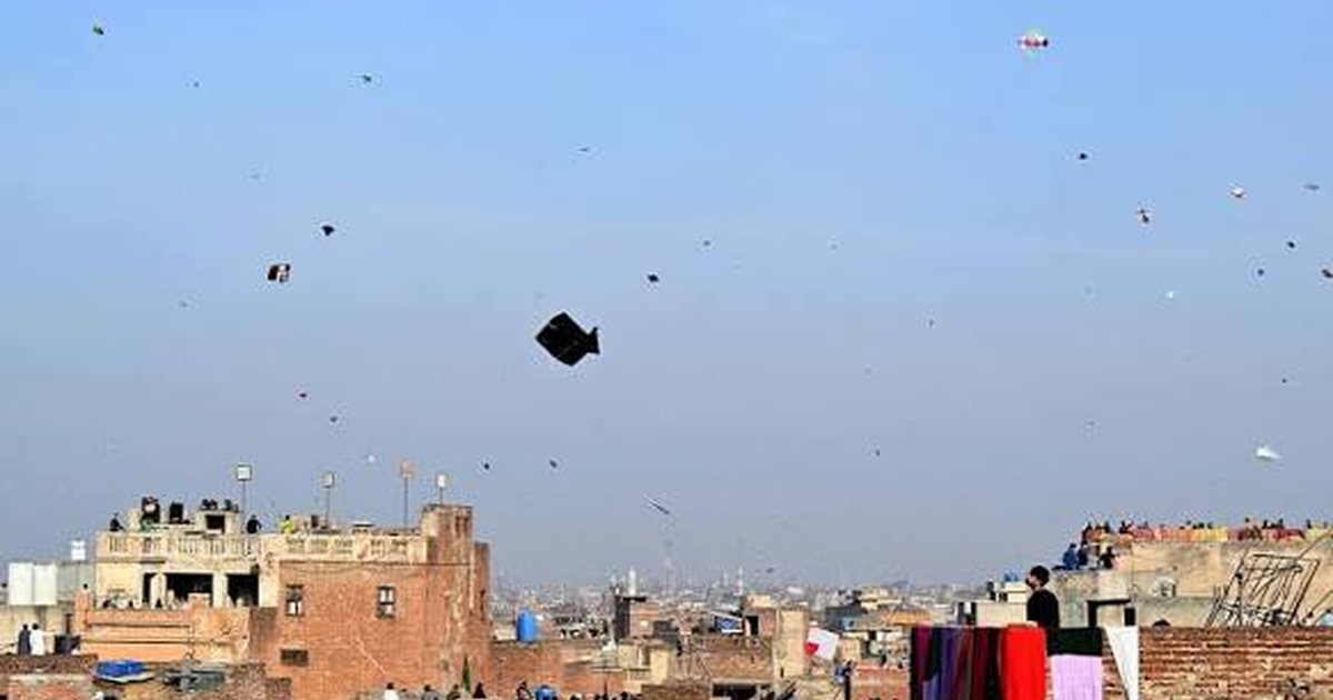Kites flying above the rooftops of Lahore against a blue sky