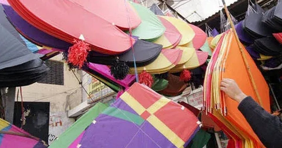 Paper guddas in pink, purple and orange hanging at a Lahore kite stall