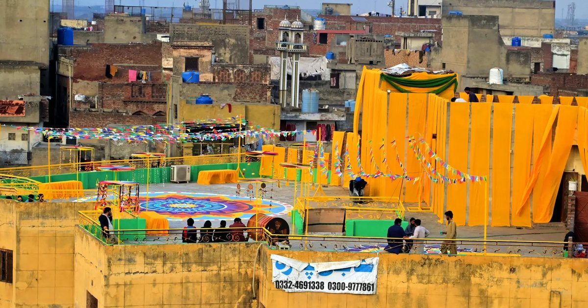 A rooftop in Lahore decorated in yellow for Basant, with the old city behind