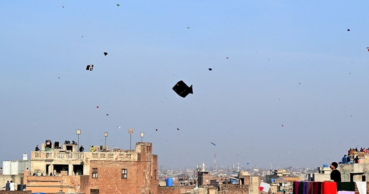 Cut kites drifting down over Lahore rooftops and the streets below, Basant 2026